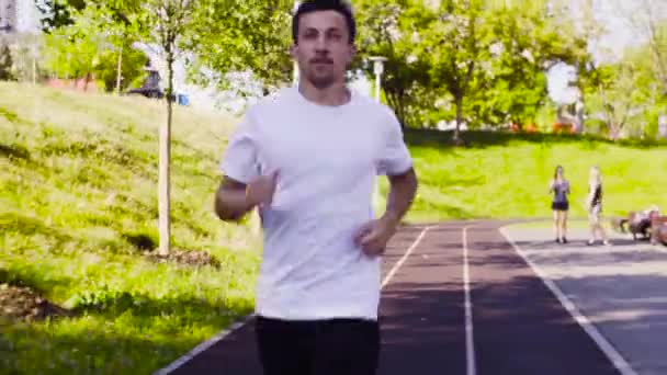 Hombre corriendo en el camino para los corredores en el estadio — Vídeos de Stock