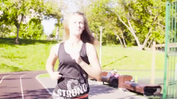 Mujer joven corriendo en el campo de deportes — Vídeos de Stock