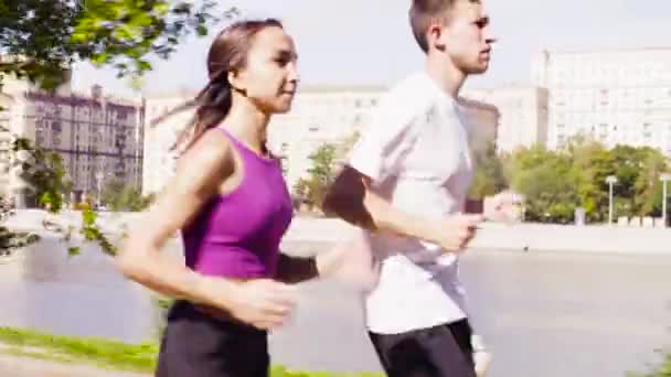Mujer y hombre corriendo en la ciudad cerca del río — Vídeos de Stock