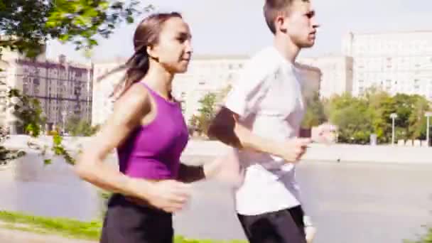 Mujer y hombre corriendo en la ciudad cerca del río — Vídeo de stock