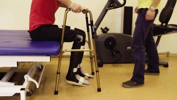 Инвалид встает с медицинского дивана, держа ходячего — стоковое видео