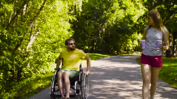 Young disable man with his wife on a walk in the park — Stock Video