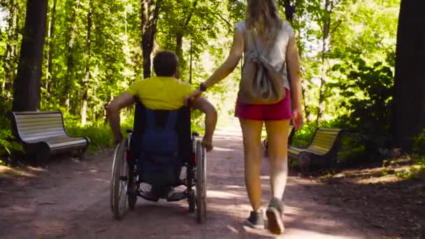 Young disable man with his wife on a walk in the park — Stock Video