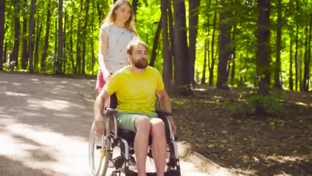 Jonge uitschakelen man op een wandeling in het park met zijn vrouw — Stockvideo