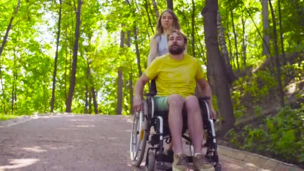 Young disable man on a walk in the park with his wife — Stock Video