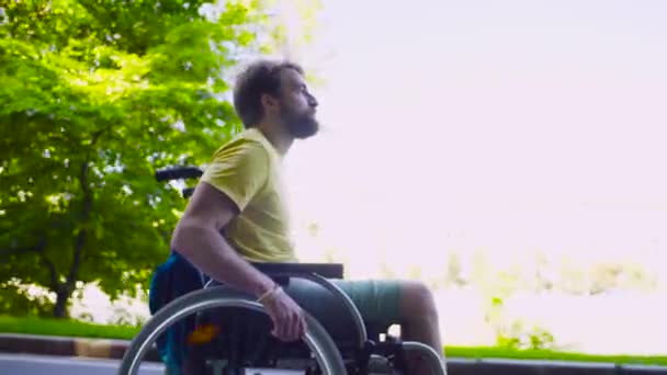 Joven hombre incapacitado en una silla de ruedas en el parque — Vídeos de Stock