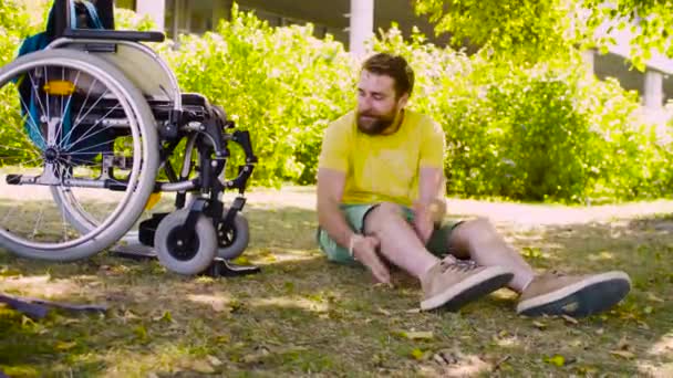 Щасливий молодий інвалід сидить на траві в парку — стокове відео