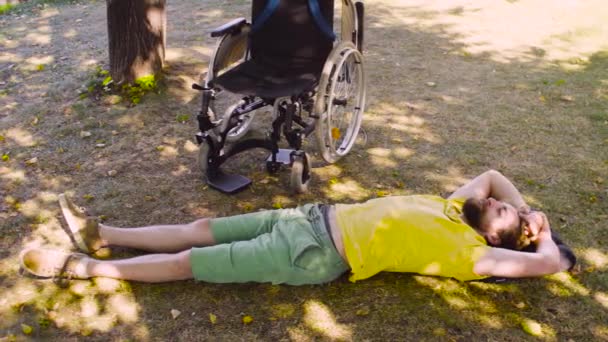 Ung inaktivera mannen är avkopplande på marken i parken — Stockvideo