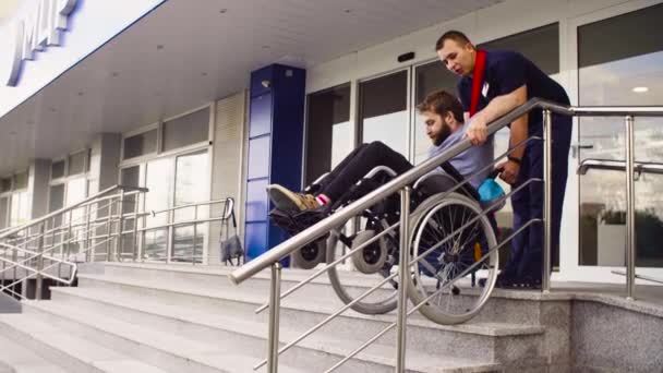 Homem ajudando a mover-se para baixo para um homem com deficiência — Vídeo de Stock