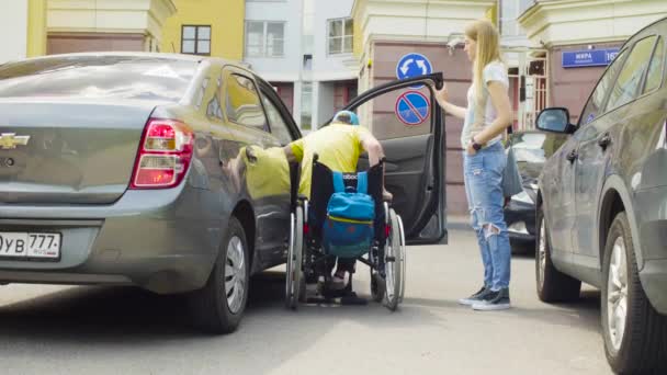 Un uomo sulla sedia a rotelle e una donna vicino alla macchina — Video Stock