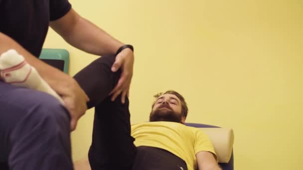 Врач помогает спортсмену-инвалиду в реабилитационном центре — стоковое видео