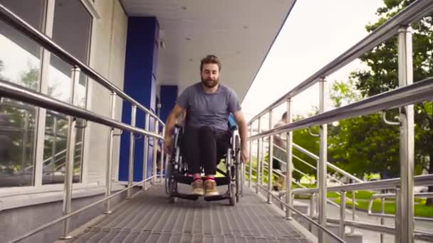Инвалид в инвалидном кресле едет по склону — стоковое видео