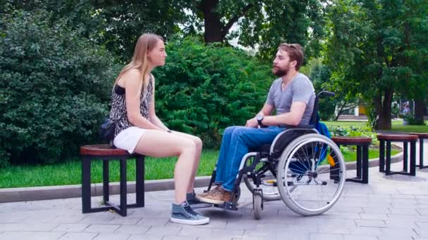 Молодой инвалид с женой, сидящей в парке — стоковое видео