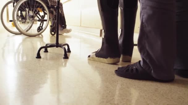 Legs of invalid in orthosis walking with support of two walking cane — Stock Video