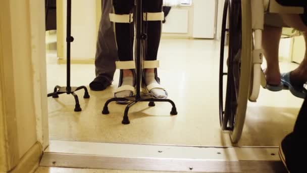 Beine von Invaliden im orthesen Gehen mit Unterstützung von zwei Gehstöcken — Stockvideo