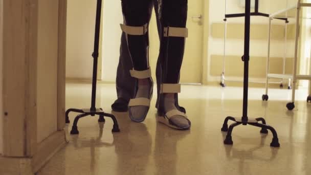 Legs of invalid in orthosis walking with support of two walking cane — Stock Video