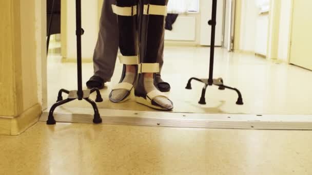 Gambe di invalido in ortesi che camminano con il supporto di due bastoni da passeggio — Video Stock