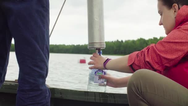 Een wetenschapper watermonster van meer gieten in plastic fles — Stockvideo