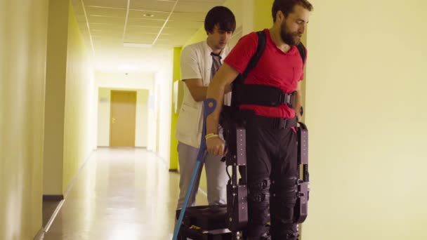 Отключить человека в роботизированном экзоскелете садится на скамейку — стоковое видео