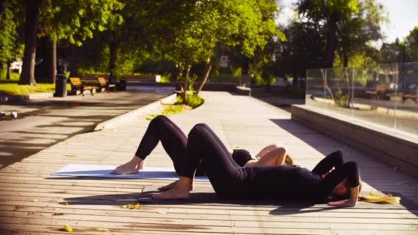 Du yoga. Deux jolies femmes faisant des exercices de yoga dans le parc — Video