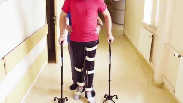 Ongeldig in de orthese wandelen met steun van twee walking cane — Stockvideo