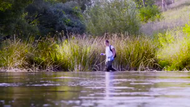 Woman ecologist in high rubber boots walking in the water of the forest river — Stock Video