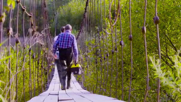 Deux scientifiques écologistes en bottes hautes en caoutchouc marchant sur un pont suspendu — Video