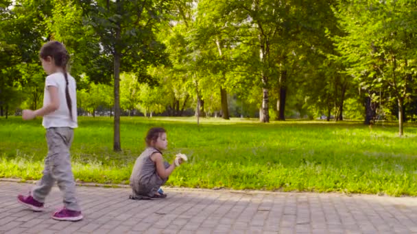 Drei Mädchen essen Bananen während eines Spaziergangs im Park — Stockvideo