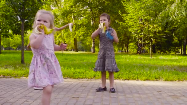 Drie meisjes lopen in het park en het eten van bananen — Stockvideo