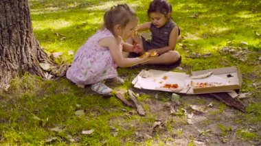 İki kız parkta pizza yemek.
