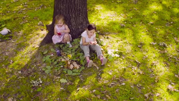 Deux filles assises dans le parc et mangeant du grenat 