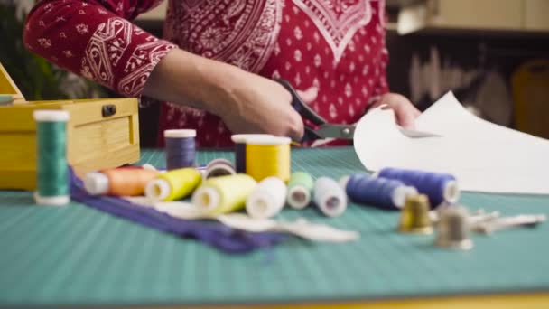 Жінка середнього віку рук з ножицями, що вирізають паперовий візерунок. Одяг ручної роботи . — стокове відео