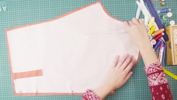 Μέσης ηλικίας γυναίκα χέρια καρφώνει ένα μοτίβο χαρτί με το ύφασμα με καρφίτσες — Αρχείο Βίντεο