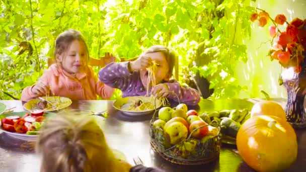 Deux vilaines filles sont assises à la table et mangent des pâtes et des saucisses frites — Video