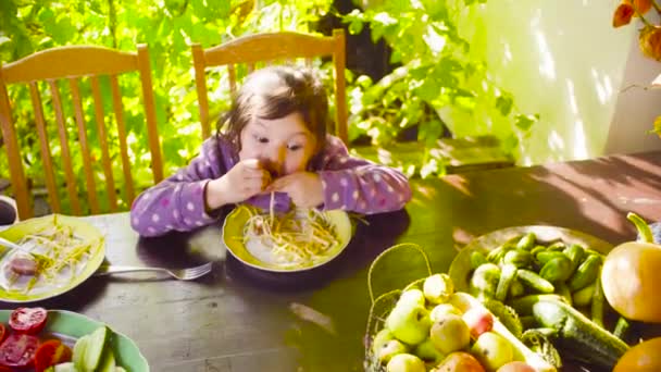 Niña está sentada en la mesa y comiendo pasta — Vídeo de stock