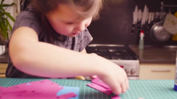 Маленькая девочка склеивает цветную бумагу — стоковое видео