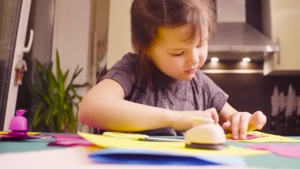 Маленькая девочка склеивает и режет цветную бумагу — стоковое видео