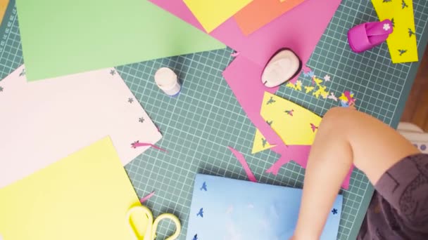 Руки маленькой девочки склеивают цветную бумагу — стоковое видео
