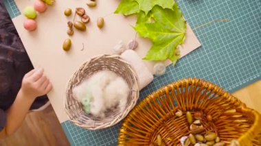 Küçük kız masa başında oturan meşe palamutları kolye yapar