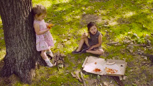 Deux filles dans le parc mangeant de la pizza .