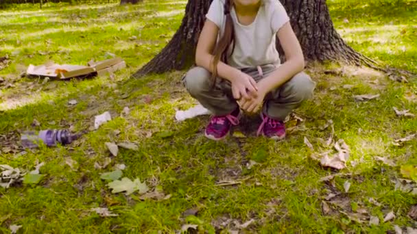 Une fille assise dans le parc sur l'herbe près de l'arbre 