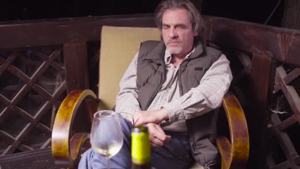 Senior sitzt im Stuhl, trinkt Wein und raucht — Stockvideo