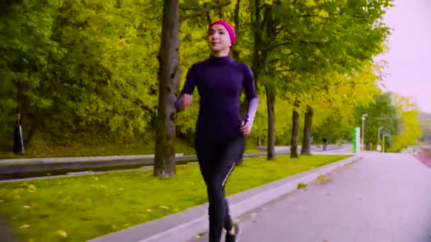 Una joven corriendo por el parque. Otoño. Aptitud — Vídeos de Stock