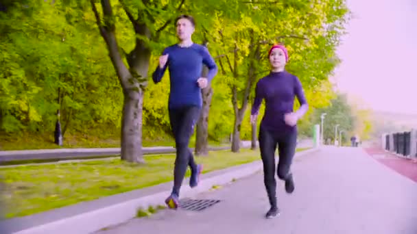 Mujer joven y hombre corriendo en el parque. Otoño . — Vídeos de Stock
