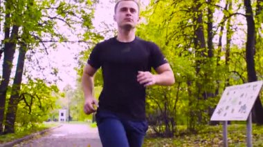 Atış, ağır çekim dolly. Sonbahar gün parkta koşan genç adam