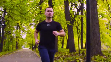 Parkta koşan genç adam. Sonbahar