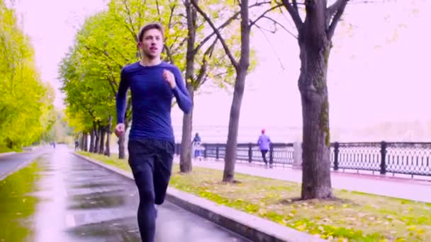 Un joven corriendo por el parque. Otoño — Vídeo de stock