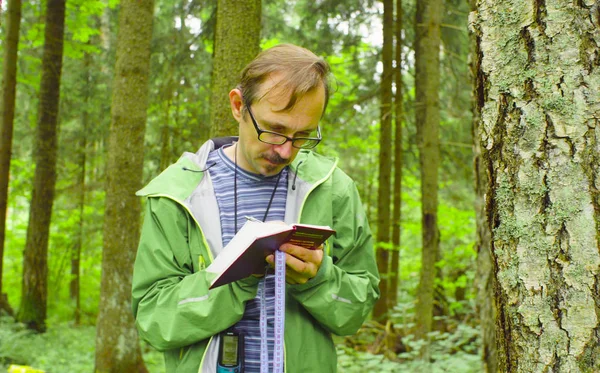 Der Ökologe im Wald schreibt ins Notizbuch. — Stockfoto