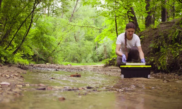Vrouw ecoloog openen een gereedschapskist en monsterneming van water — Stockfoto
