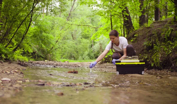 Žena ekolog odběru vzorků vody z potoka — Stock fotografie
